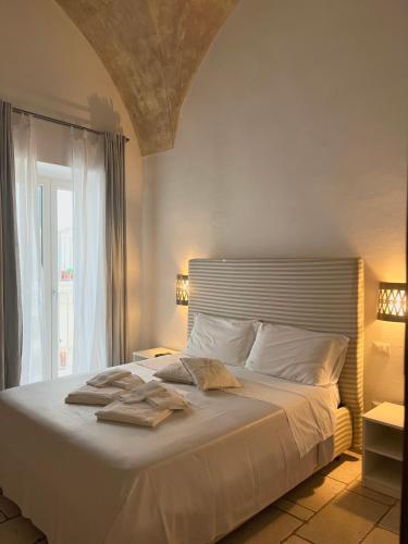 ein Schlafzimmer mit einem Bett mit weißer Bettwäsche und einem Fenster in der Unterkunft B&B Finestra Sul Mare in Gallipoli