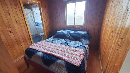 małą sypialnię z łóżkiem w drewnianym pokoju w obiekcie CASA DE HUÉSPEDES JEM w mieście Bucalemu