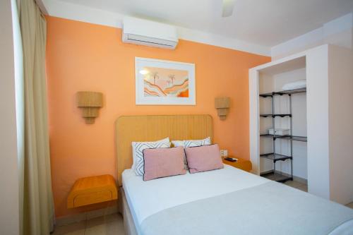 a bedroom with orange walls and a bed with two pillows at Hotel Tropicus Boutique in Puerto Vallarta