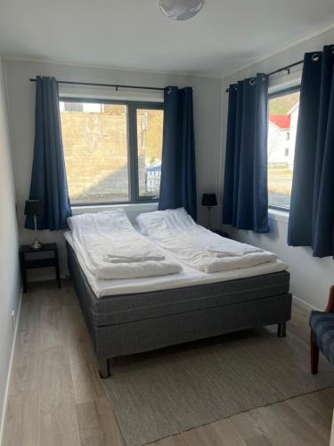 1 dormitorio con 1 cama con cortinas azules y ventana en Mosjøen Romutleie - Sentrum 2 en Mosjøen