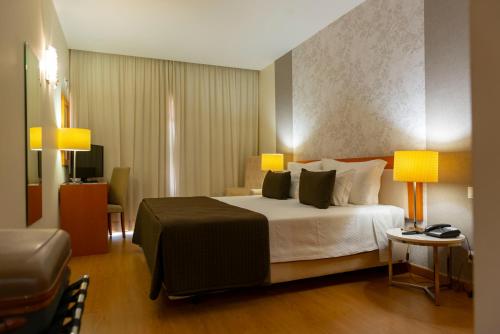 a bedroom with a bed with two lamps and a chair at Eurosol Residence Hotel Apartamento in Leiria