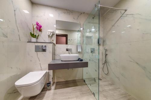 W łazience znajduje się toaleta, umywalka i prysznic. w obiekcie Hotel Kiparis Alfa w mieście Smolan
