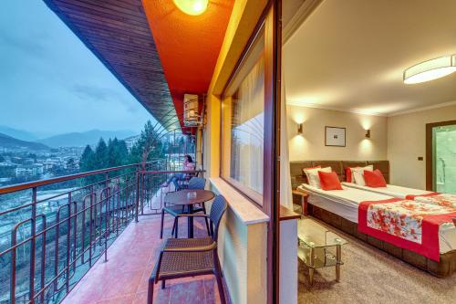 Un balcón de una habitación de hotel con una cama y una mesa en Hotel Kiparis Alfa en Smolyan