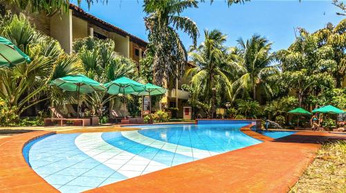 a resort swimming pool with green umbrellas and palm trees at Solar Pipa - Solar da Gameleira Flats in Pipa