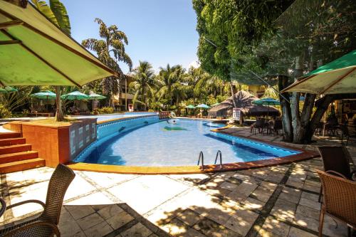 een zwembad met stoelen en parasols in een resort bij Solar Pipa - Solar da Gameleira Flats in Pipa