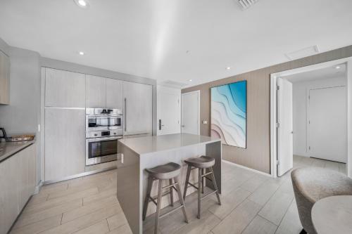 a kitchen with a counter and stools in a room at Wake Up To Ocean Views - Stunning 2BDR & 2BA Condo STEPS AWAY FROM THE OCEAN in Hollywood