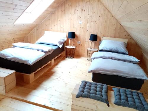 two beds in a room with wooden walls at Apartmány Statek u Dobráka in Třeboň