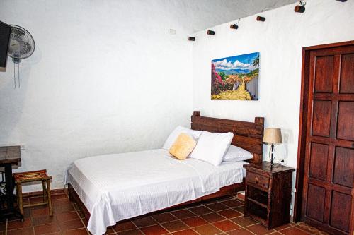 a bedroom with a bed and a painting on the wall at Hotel Campestre Ataraxia Barichara in Barichara