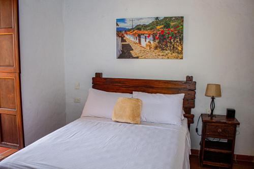 a bedroom with a bed and a painting on the wall at Hotel Campestre Ataraxia Barichara in Barichara