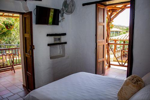 a bedroom with a bed and a tv and a balcony at Hotel Campestre Ataraxia Barichara in Barichara