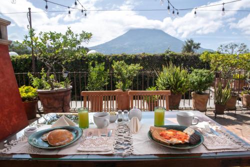 a table with plates of food and a mountain in the background at Posada del Angel in Antigua Guatemala