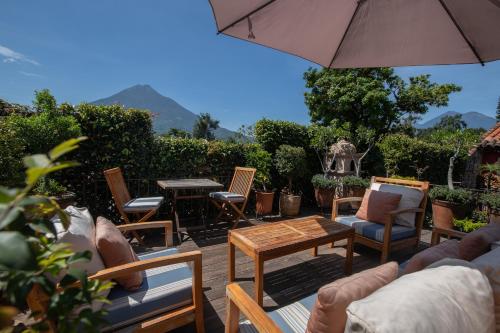 un patio con sillas, mesas y una sombrilla en Posada del Angel en Antigua Guatemala