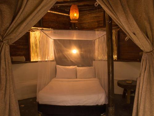 a bedroom with a canopy bed with white sheets and pillows at Rio Elemento in Minca
