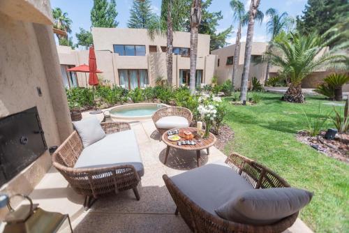 a patio with chairs and a table and a pool at La Maria Hotel Boutique in Chacras de Coria