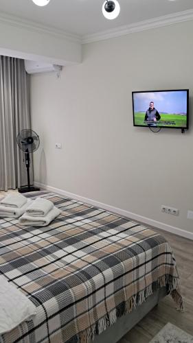 a bedroom with a bed with a tv on the wall at AIRPORT&APARTMENT&parking in Chişinău