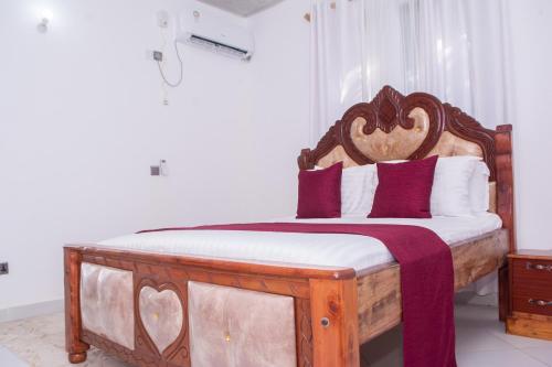 a bedroom with a wooden bed with purple pillows at Baali Diani Apartments in Ukunda