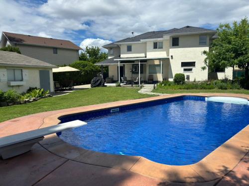 a large blue swimming pool in front of a house at Park side Basement 2 bedroom suite in Kelowna