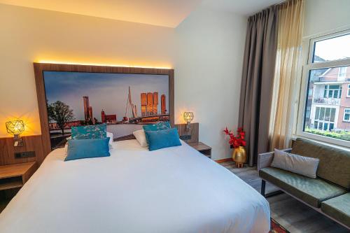 a bedroom with a large white bed with blue pillows at Hotel Milano in Rotterdam