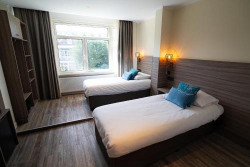 a hotel room with two beds and a window at Hotel Milano in Rotterdam