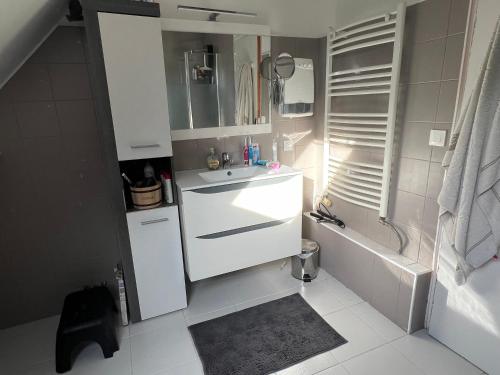 La salle de bains blanche est pourvue d'un lavabo et d'une baignoire. dans l'établissement Maison familiale proche Arpajon, à Égly