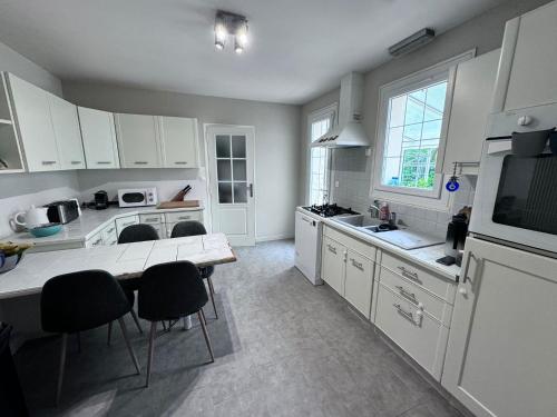 une cuisine avec des armoires blanches et une table et des chaises dans l'établissement Maison familiale proche Arpajon, à Égly