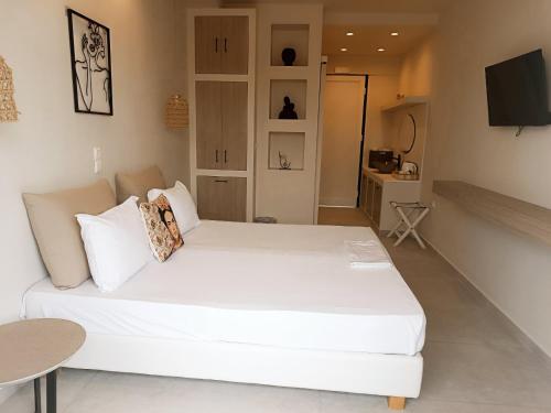 uma cama branca num quarto com uma televisão em Akrogiali em Skala