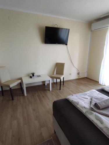 Habitación con cama y TV en la pared. en Ema Apartmani en Vinkovci