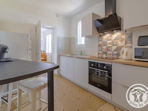 une cuisine avec des armoires blanches et un four à plaques de cuisson dans l'établissement Charmante Maison de Plain-Pied, Proche Commerces et Activités, Entre Nantes et Cholet - FR-1-622-82, à Saint-Germain-sur-Moine