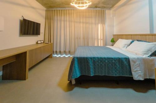 a bedroom with a large bed and a desk at Apartamento Luxo Central - CA704 in Maringá