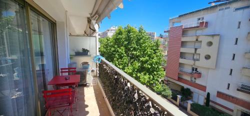 - un balcon avec une table et des chaises rouges et un bâtiment dans l'établissement Magnifique studio Juan les pins-plage à pied, à Antibes