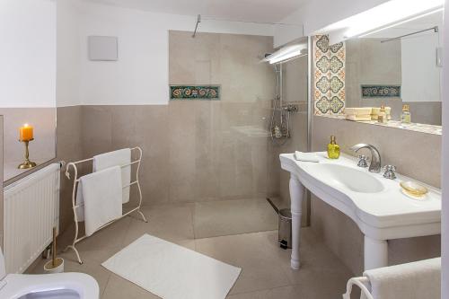 La salle de bains blanche est pourvue d'un lavabo et d'un miroir. dans l'établissement Getreidegassen Appartements, à Salzbourg