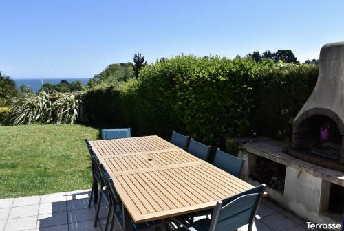 a wooden table and chairs on a patio with a fireplace at Magnifique maison vue mer in Ploubazlanec