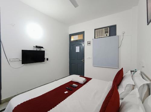 a bedroom with a bed and a tv and a door at Hotel Hauz Khas Fort View in New Delhi