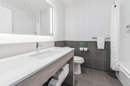 La salle de bains blanche est pourvue d'un lavabo et de toilettes. dans l'établissement Holiday Inn Express Hotel & Suites Saint - Hyacinthe, an IHG Hotel, à Saint-Hyacinthe