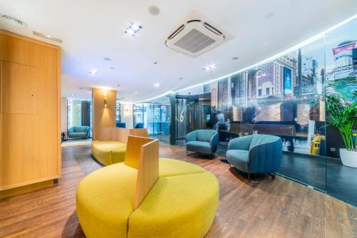 a waiting room with a yellow chair and chairs at Hotel Indigo Madrid - Gran Vía by IHG in Madrid