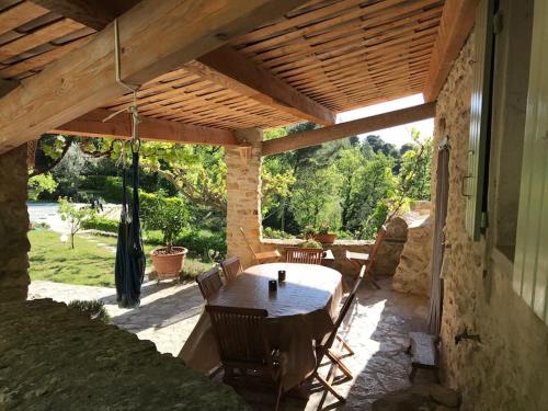 eine Terrasse mit einem Tisch und Stühlen unter einem Holzdach in der Unterkunft Mas in the Provence in Nyons