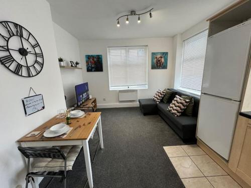 a living room with a table and a clock on the wall at Luton Centre Apartment in Luton