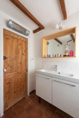 La salle de bains est pourvue d'un lavabo et d'une porte en bois. dans l'établissement Mas in the Provence, à Nyons