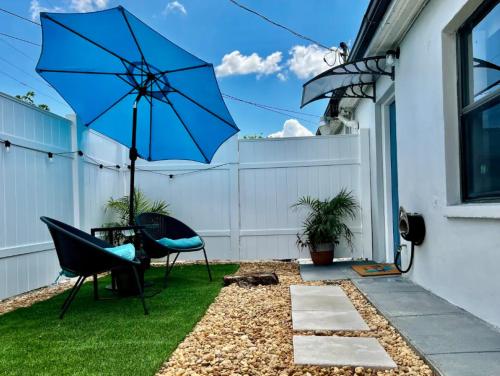 a patio with a blue umbrella and a chair at Coastal Retreat by TPA & Stadium in Tampa