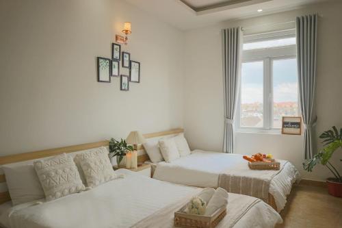 a bedroom with two beds and a couch and a window at Huong Anh DaLat Palace in Da Lat