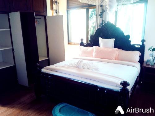 a bedroom with a large bed with white sheets and pink pillows at DISCOVERY COURTS HOTEL in Entebbe