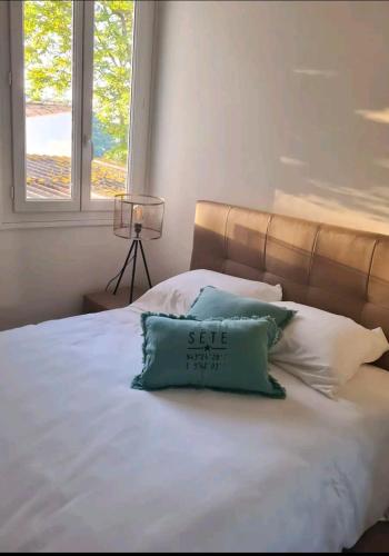- un lit avec un oreiller bleu assis au-dessus dans l'établissement Maisonnette Saint Clair, la vie est belle!, à Sète