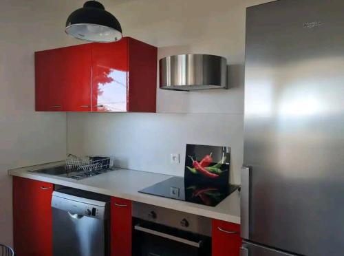 une cuisine avec des armoires rouges et un comptoir dans l'établissement Maisonnette Saint Clair, la vie est belle!, à Sète