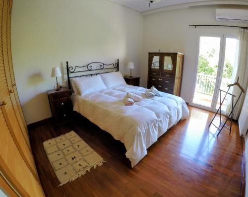 a bedroom with a large white bed and wooden floors at Σπίτι στο Ρίο Πατρών με κήπο - Detached House In Rio With Garden in Rio