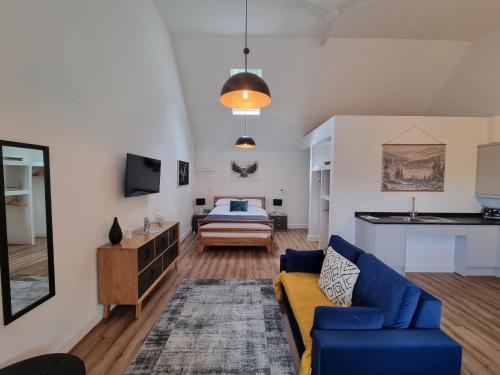 a living room with a blue couch and a bed at Blundens Holiday Lets - Tower in Boxgrove