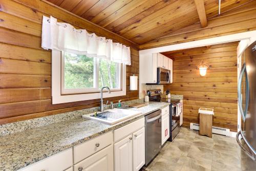 cocina con paredes de madera, lavabo y ventana en Cozy Lake Champlain Cottage with Private Beach!, en North Hero
