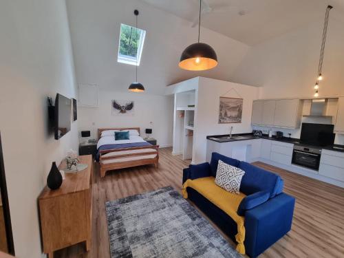 a living room with a blue couch and a bed at Blundens Holiday Lets - Tower in Boxgrove