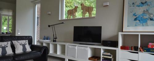 a living room with a television on a white entertainment center at Vakantiehuis Leukderhuisje Geulle Meerssen in Guelle