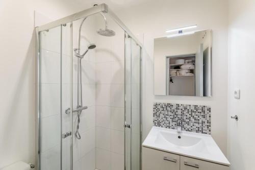 une salle de bain blanche avec une douche et un lavabo dans l'établissement Studio proche Plage du Mourillon Confort et Charme, à Toulon