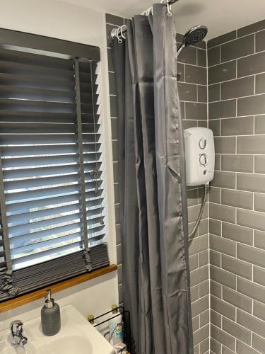 cortina de ducha en el baño con lavamanos en Elmwood Lodge, en Kent